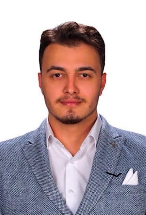 Portrait of Ayhan Uzundal wearing a blue-grey jacket and a white shirt